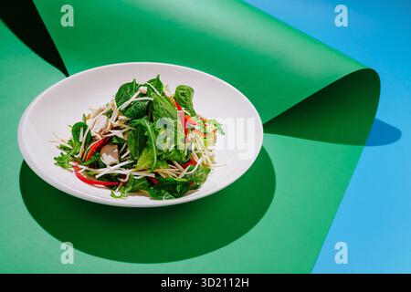 Salade verte fraîche avec des légumes vibrants sur une toile de fond colorée affichée dans un cadre lumineux Banque D'Images
