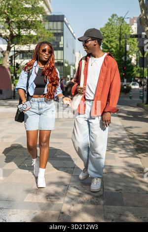 Rire parlant romantique couple afro-américain marchant dans les rues de la ville, plaisantant ensemble Banque D'Images