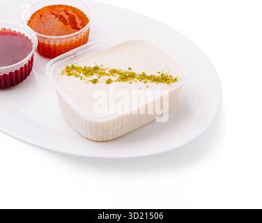 Plateau de desserts avec pudding crémeux aux pistaches et deux sirops de fruits vibrants à une table à manger Banque D'Images