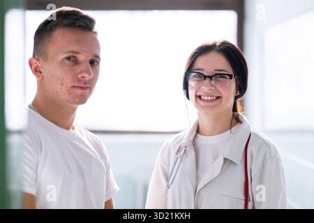 Professionnels de la santé masculins et féminins souriants et debout ensemble dans un couloir d'hôpital. Concept de travail d'équipe et de soins. Banque D'Images