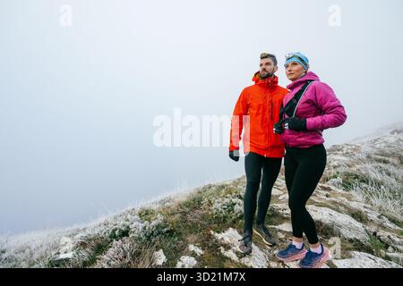 Randonneurs posant sur Foggy Mountain Top.Portrait de deux randonneurs posant ensemble sur un haut de montagne brumeux portant des équipements de plein air. Banque D'Images