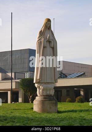 Statue de la Vierge Marie priant devant une église moderne Banque D'Images