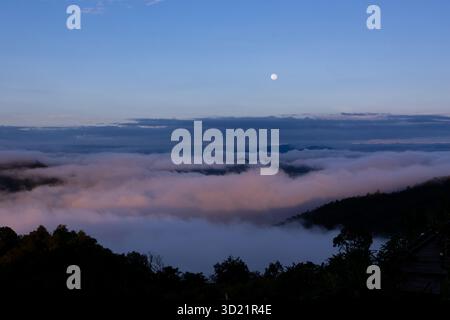 Une belle vue en angle le matin, la mer embuant sur les sommets des montagnes, vous pouvez voir la lune briller encore brillamment, fournissant des connaissances Banque D'Images
