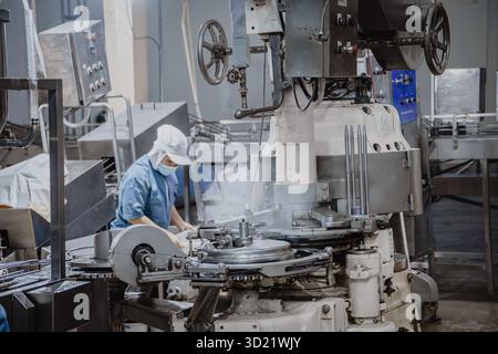 Usine silencieuse, peu de travailleurs de l'usine nettoyant la chaîne de production transportent la bande se préparent à fermer l'usine alimentaire fermée Banque D'Images
