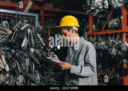 Technicien ouvrier masculin travaillant dans l'entrepôt d'atelier de vieil atelier de pièces de voiture de cour de ferraille de garage Banque D'Images