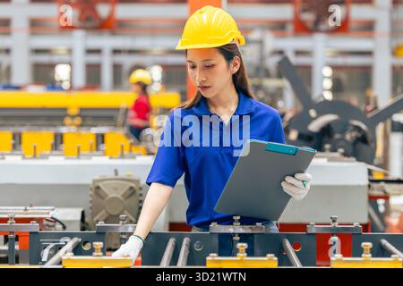 Jeune femme asiatique adolescente ouvrière d'ingénieur, machine professionnelle de vérification de travail féminine dans l'usine de tôle métallique, personnel de l'industrie de technicien de sécurité Banque D'Images