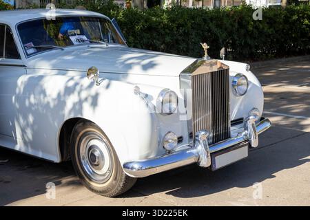 Prestigieuse automobile classique debout à l'extérieur sous la lumière du soleil, mettant en valeur sa calandre emblématique, son ornement de capot et ses détails chromés Banque D'Images