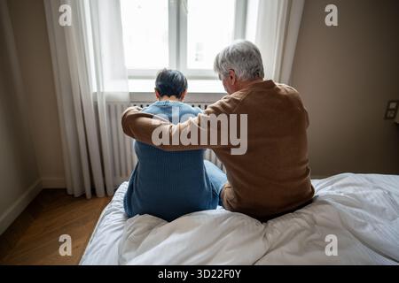 Perte dans la famille âgée, couple embrassant comme homme réconforte la femme en deuil, fournissant un soutien émotionnel Banque D'Images