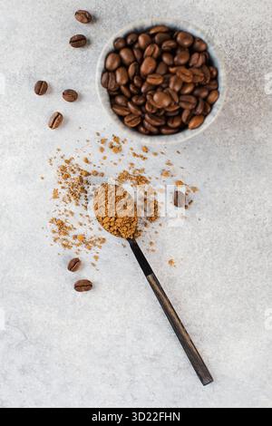 Grains de café torréfiés et cuillère avec granulés de boisson instantanée sur table gris clair Banque D'Images