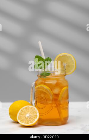 Un verre de thé froid, des glaçons, des tranches de citron et une branche de menthe. Des boissons rafraîchissantes en été. Banque D'Images