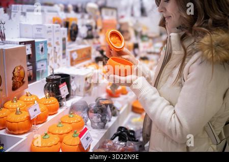 À la veille d'Halloween, une femme parcourt un marché local, sélectionnant des citrouilles en céramique colorées et des pots uniques pour la décoration intérieure. Elle aime la fête Banque D'Images