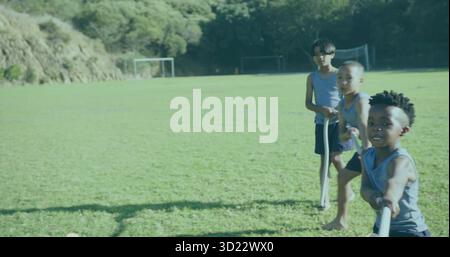 Trois amis jouant au remorqueur de la guerre avec une longue corde sur un terrain de football en herbe près des poteaux de but, espace de copie Banque D'Images