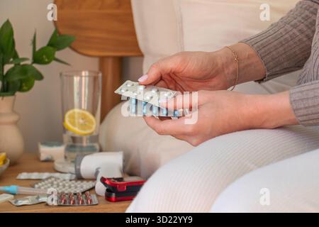 Femme tenant différents blister paquets de médicaments à la maison pour le traitement. Médecine Banque D'Images