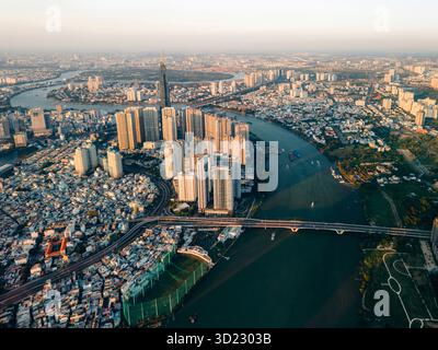 Vue aérienne d'un paysage urbain dynamique avec des gratte-ciel et une rivière sinueuse au coucher du soleil. Ho Chi Minh ville, Vietnam Banque D'Images