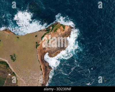 Vue aérienne d'une falaise côtière rocheuse avec des vagues s'écrasant contre le rivage. Lombok, Sekaroh, Indonésie Banque D'Images