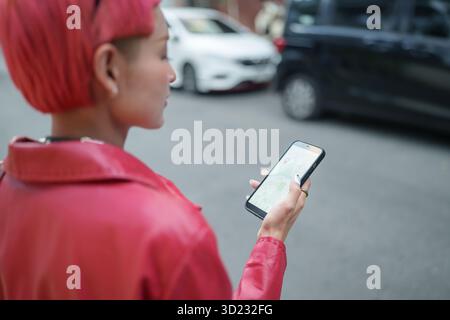 Traveler Gen z Girl mode en cuir avec punk asiatique femme touriste dans la rue de la ville recherche l'emplacement dans la carte application en ligne s Banque D'Images