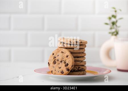 Les biscuits sont étalés sur une assiette, un verre de lait frais. Biscuits faits maison avec pépites de chocolat. Banque D'Images
