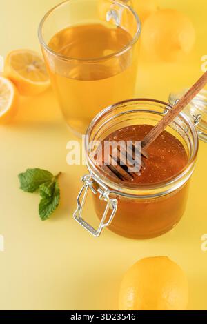 Un pot de miel avec une louche de miel avec des feuilles de menthe et des tranches de citron. Banque D'Images