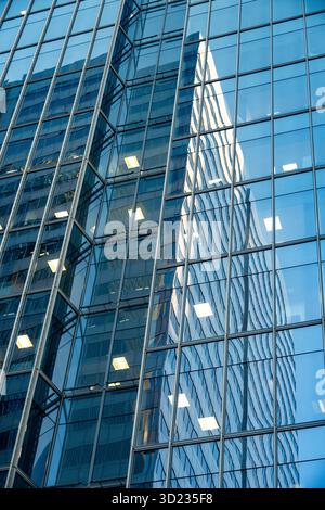 Façade en verre d'un gratte-ciel moderne reflétant un autre bâtiment dans un paysage urbain. Calgary, Alberta, Canada Banque D'Images