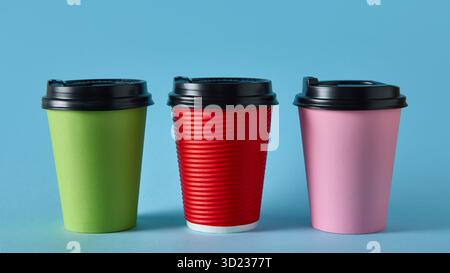 Trois tasses à café à emporter colorées avec des couvercles noirs sur fond bleu pour la conception de l'emballage Banque D'Images