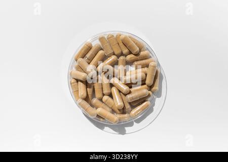 Les capsules contenant des vitamines ou un complément alimentaire sont brunes sur fond blanc. Médecine, médicaments Banque D'Images
