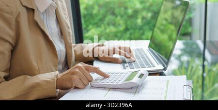 Femme d'affaires calculant l'état financier sur la calculatrice déclaration d'impôt sur le revenu en ligne et paiement. Banque D'Images