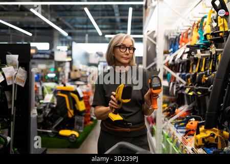 Femme magasinant pour des outils de jardin dans un grand magasin de détail se concentrant sur l'amélioration de la maison et les fournitures de plein air Banque D'Images