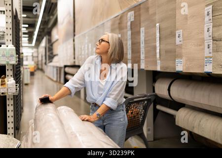 Femme sélectionnant des produits à la maison dans un magasin de détail, mettant en valeur des émotions authentiques pendant l'aventure de shopping Banque D'Images
