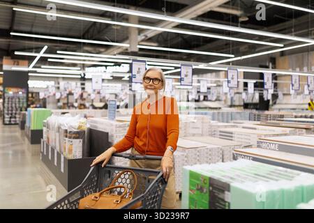 Femme sélectionnant des articles dans un hypermarché lors d'un voyage de shopping mettant en valeur une expérience de vente au détail moderne Banque D'Images