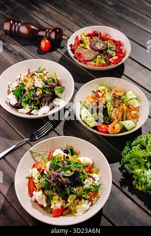 Saladiers colorés affichés sur une table en bois avec des ingrédients frais Banque D'Images