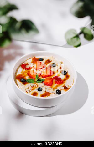 Délicieux bol de flocons d'avoine garni de fruits frais et de sirop sur une table Banque D'Images