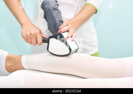 Technicien féminin effectuant l'épilation au laser sur les jambes féminines caucasiennes Banque D'Images