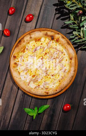 Délicieuse pizza garnie de fromage et de jambon sur une table rustique en bois Banque D'Images