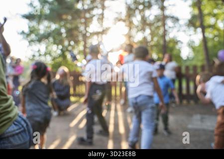 Image floue d'un groupe diversifié d'enfants jouant à l'extérieur dans un parc ensoleillé Banque D'Images