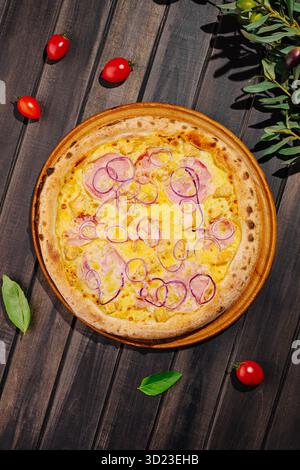 Délicieuse pizza garnie de fromage, jambon et oignons sur une table en bois rustique Banque D'Images