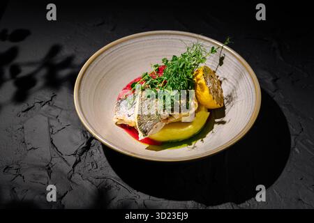 Poisson grillé servi sur purée vibrante avec herbes fraîches et citron Banque D'Images