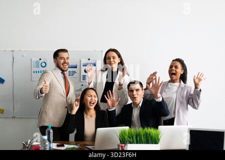 Un groupe d'hommes d'affaires collègues debout dans le bureau à des ordinateurs portables avec un sourire souriant à la caméra Banque D'Images