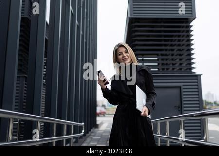 Une femme d'affaires tient un téléphone dans sa main et parle avec un partenaire sur une connexion cellulaire dans le contexte d'une entreprise Banque D'Images