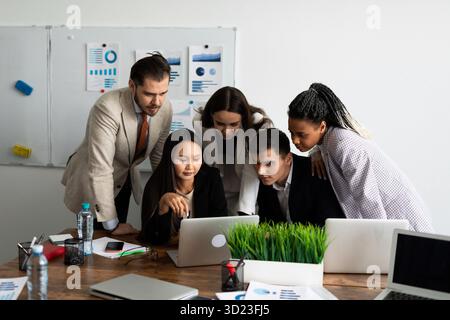 Une équipe de développeurs est engagée dans un projet tout en regardant un moniteur d'ordinateur portable ensemble Banque D'Images