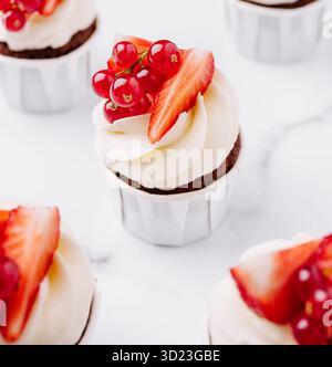 Délicieux cupcakes garnis de fraises fraîches et de groseilles pour le dessert Banque D'Images