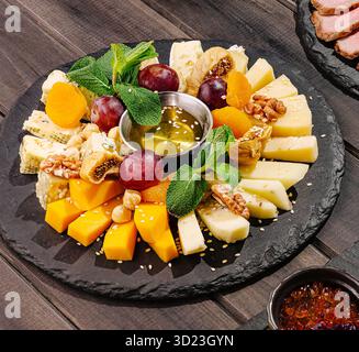 Plateau de fromage et de fruits avec miel servi sur une planche d'ardoise lors d'une réunion Banque D'Images