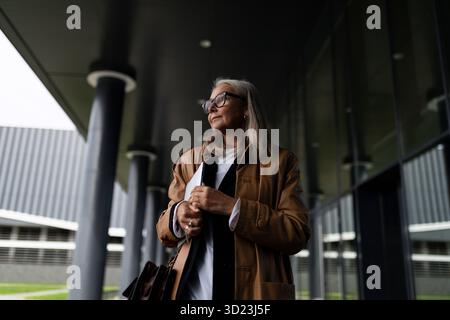 Femme d'affaires âgée à l'entrée de l'immeuble de bureaux avec une tablette dans ses mains Banque D'Images