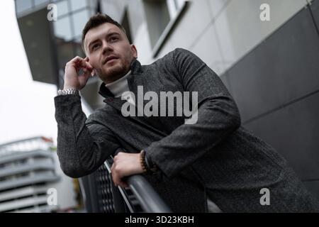 Portrait d'un homme d'âge moyen élégant et brutal sur le fond d'un mur de bâtiment gris Banque D'Images