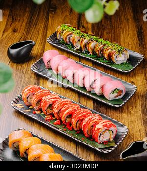 Plateaux de sushi avec des rouleaux assortis affichés sur une table en bois Banque D'Images