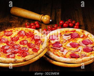 Deux délicieuses pizzas garnies de pepperoni et de jambon sur une table en bois Banque D'Images