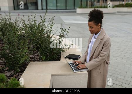 Jeune femme afro-américaine travaillant sur ordinateur portable à l'extérieur du bureau Banque D'Images
