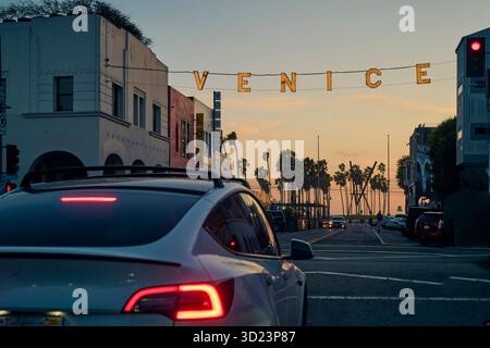 Rue de Venise au crépuscule avec des voitures et des palmiers silhouettés contre un ciel de coucher de soleil. Californie, États-Unis Banque D'Images