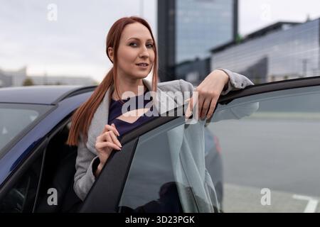 Femme d'affaires sortant de la voiture avec la toile de fond d'un immeuble de bureau Banque D'Images