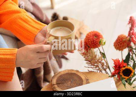Mains féminines avec tasse de café à la maison le jour d'automne, gros plan Banque D'Images