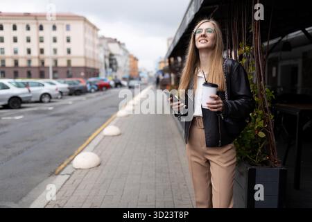 Jeune femme d'affaires au téléphone dans ses mains et une tasse de café Banque D'Images